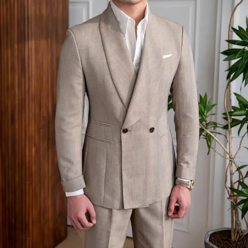 Un homme portant un élégant costume beige croisé avec un revers châle, assorti à une chemise blanche impeccable, dans un intérieur lumineux et raffiné, dégageant un style classique et moderne.