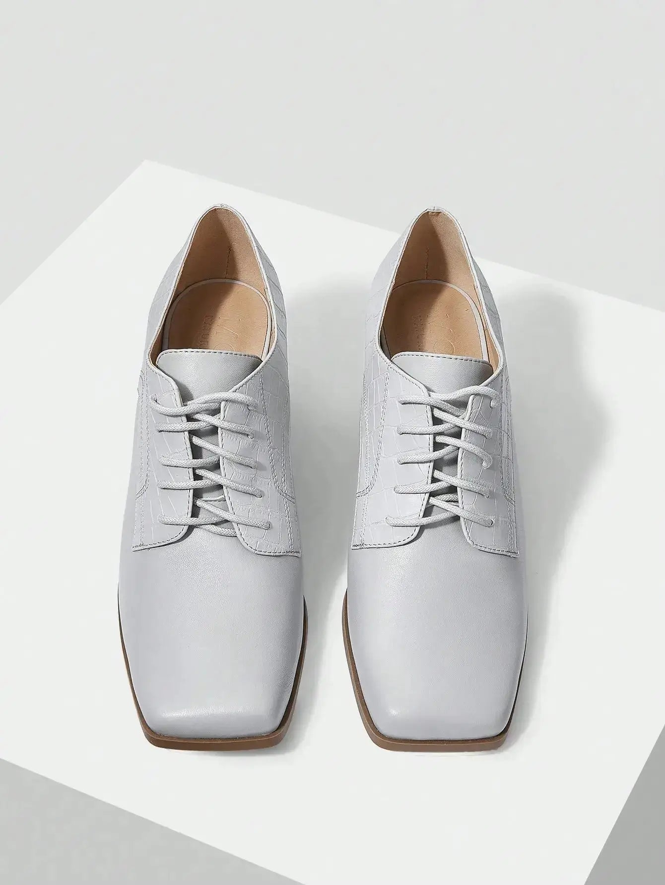 Chaussures Anglaise Talon Carré en similicuir haut de gamme. Design épuré avec bout carré et talon épais de hauteur moyenne pour un confort optimal. Disponible en gris classique, ces chaussures présentent un motif uni et des lacets raffinés. Pour l'entretien, nettoyer avec un chiffon doux et sec.