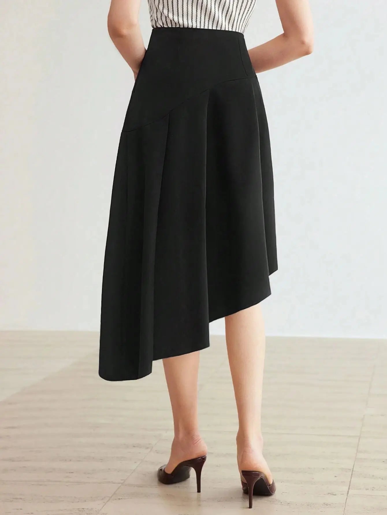 Jupe asymétrique noire en 92 % polyester et 8 % élasthanne. Coupe mi-mollet fluide avec coutures stylisées et bords inégaux pour un look moderne. Lavage à la main ou en machine recommandé.