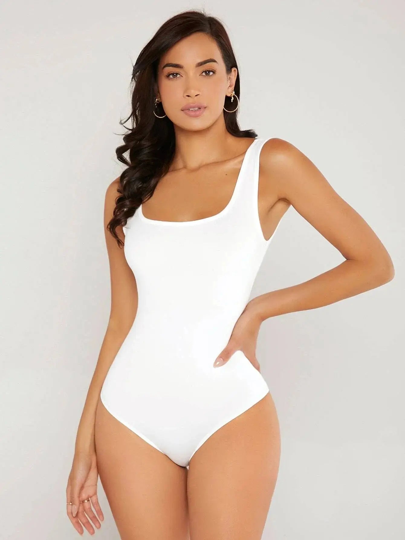 Body à col carré confectionné en polyester (95%) et spandex (5%). Présente une coupe ajustée avec manches longues pour une silhouette chic. Disponible en blanc pur et noir profond. Caractérisé par des finitions fines, coutures discrètes et un excellent maintien. Entretien : lavage à la main ou en machine à froid, cycle délicat.