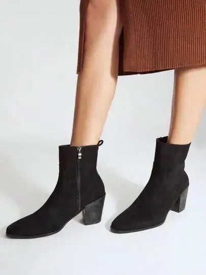 Bottines noires en imitation daim de qualité supérieure. Design élégant avec bout légèrement pointu et fermeture éclair latérale. Talons carrés pour un confort optimal et texture veloutée pour un effet luxueux. Nettoyage à sec recommandé pour maintenir l'éclat du matériau.