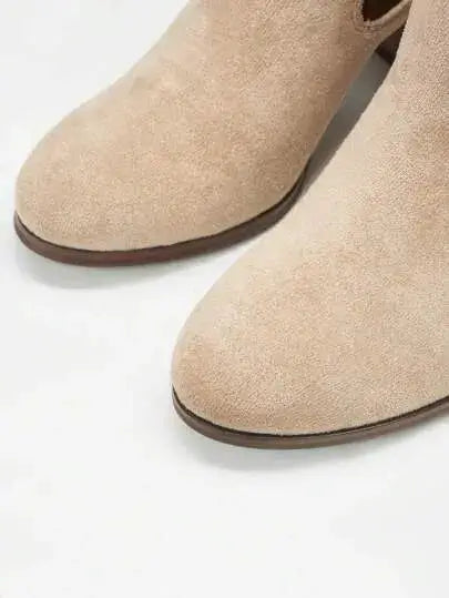 Bottines Chelsea à talon en suédine beige sable, agrémentées d'élastiques latéraux marron foncé. Design épuré à enfiler avec boucle arrière et talon bloc carré de hauteur moyenne. Construction extérieure et doublure en suédine, semelle extérieure en caoutchouc, semelle intérieure en similicuir. Style minimaliste et polyvalent. Entretien : nettoyage à sec recommandé.