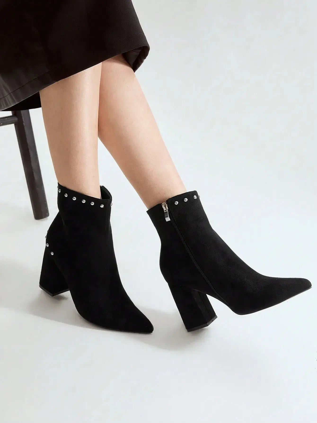 Bottines en suédine noire de qualité supérieure, au design chic avec un bout légèrement pointu et une fermeture éclair latérale. Ornées de clous décoratifs pour un style audacieux, elles possèdent un talon carré épais garantissant confort et stabilité. Couleur noire classique. Nettoyage à la main recommandé pour préserver l'apparence du faux daim.