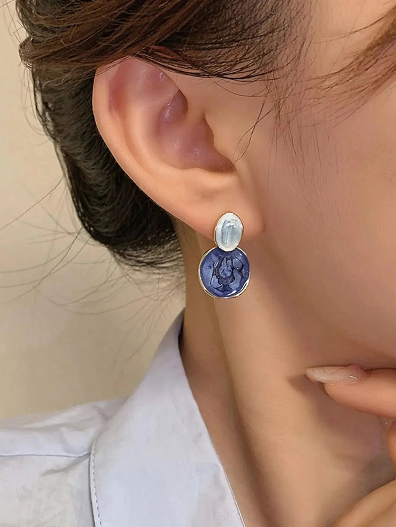 Boucles d'oreilles en alliage métallique doré et résine de qualité, disponibles en bleu clair marbré et bleu marine. Design asymétrique avec cercles marbrés superposés et bordure dorée. Nettoyage à la main conseillé pour préserver leur éclat.