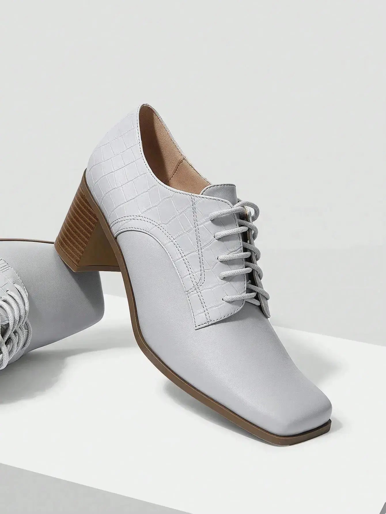 Chaussures Anglaise Talon Carré en similicuir haut de gamme. Design épuré avec bout carré et talon épais de hauteur moyenne pour un confort optimal. Disponible en gris classique, ces chaussures présentent un motif uni et des lacets raffinés. Pour l'entretien, nettoyer avec un chiffon doux et sec.