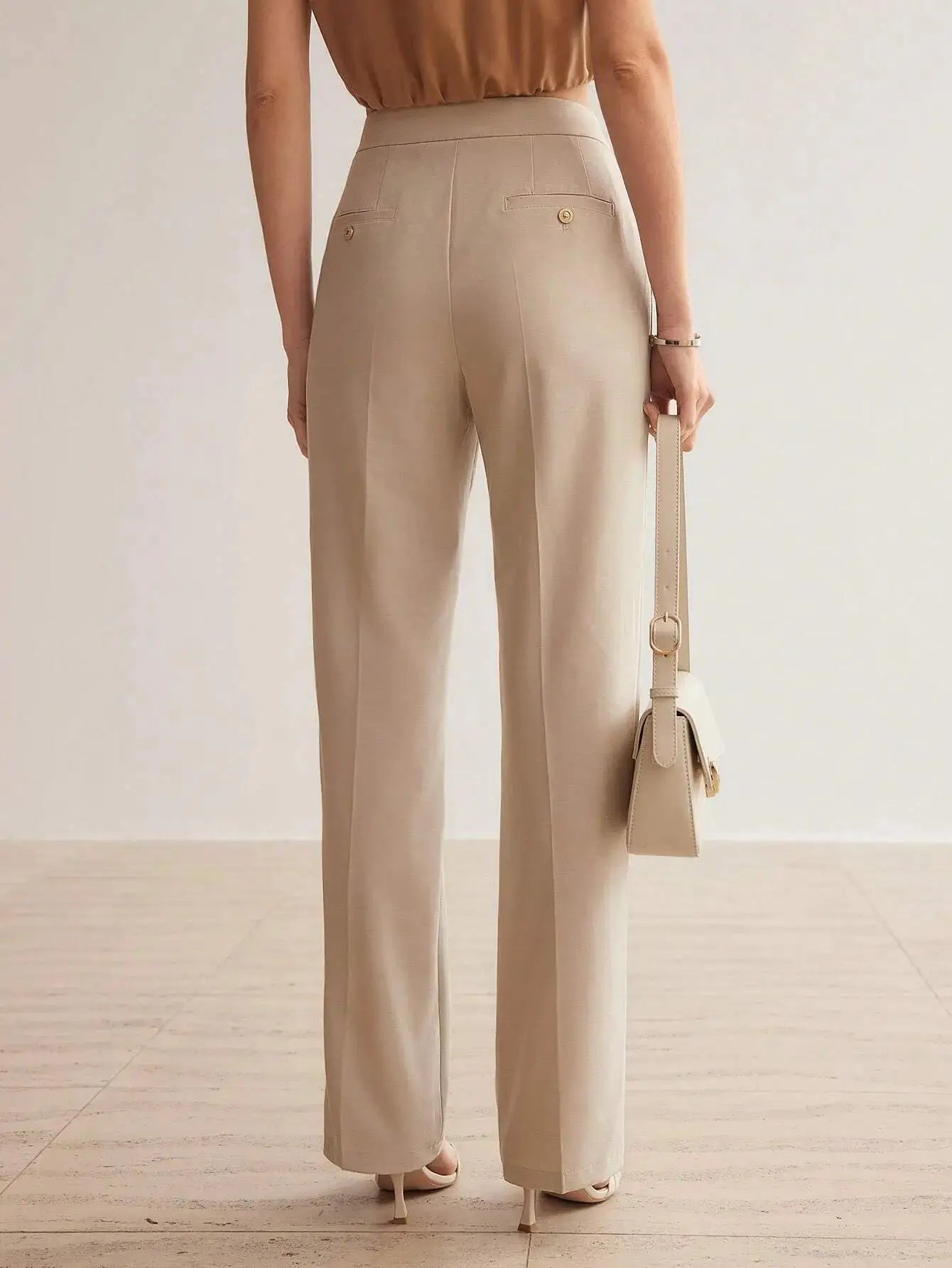 Pantalon en 100% polyester de haute qualité, offrant une texture douce et durable. Coupe droite raffinée avec fermeture éclair, rabat, et poches intégrées. Teinte beige sophistiquée. Finitions élégantes avec ceinture intégrée et plis soignés. Entretien : lavage en machine ou nettoyage à sec recommandé.