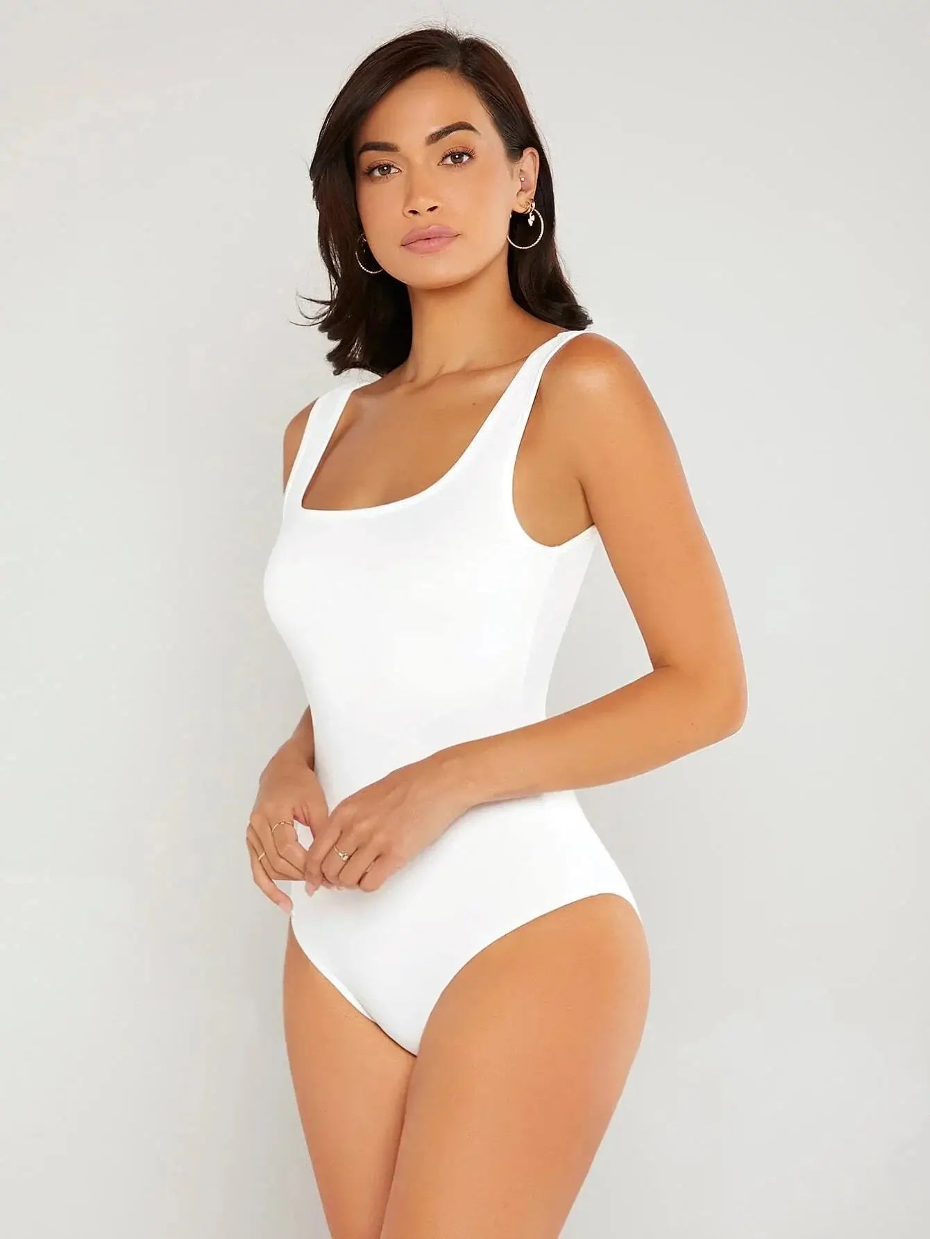 Body à col carré confectionné en polyester (95%) et spandex (5%). Présente une coupe ajustée avec manches longues pour une silhouette chic. Disponible en blanc pur et noir profond. Caractérisé par des finitions fines, coutures discrètes et un excellent maintien. Entretien : lavage à la main ou en machine à froid, cycle délicat.