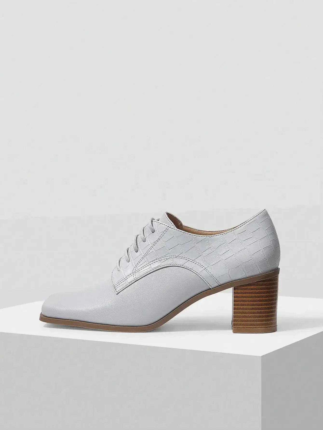 Chaussures Anglaise Talon Carré en similicuir haut de gamme. Design épuré avec bout carré et talon épais de hauteur moyenne pour un confort optimal. Disponible en gris classique, ces chaussures présentent un motif uni et des lacets raffinés. Pour l'entretien, nettoyer avec un chiffon doux et sec.