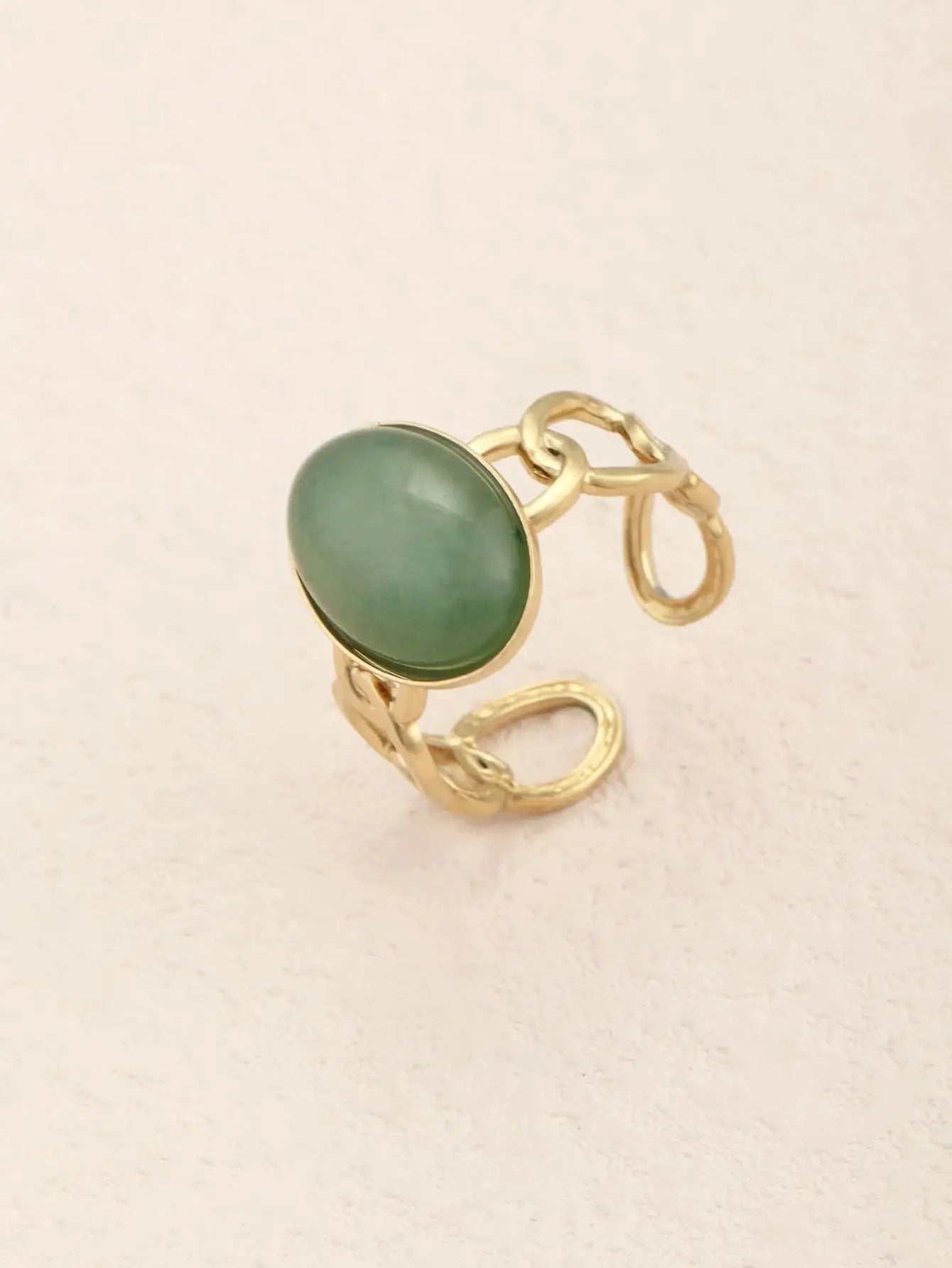 Bague ajustable en alliage de zinc plaqué or, avec une pierre ovale verte en résine. Bandeau en maillons torsadés, diamètre de 1,8 cm et poids de 3,8 g. Nettoyage à la main recommandé pour préserver l’éclat.