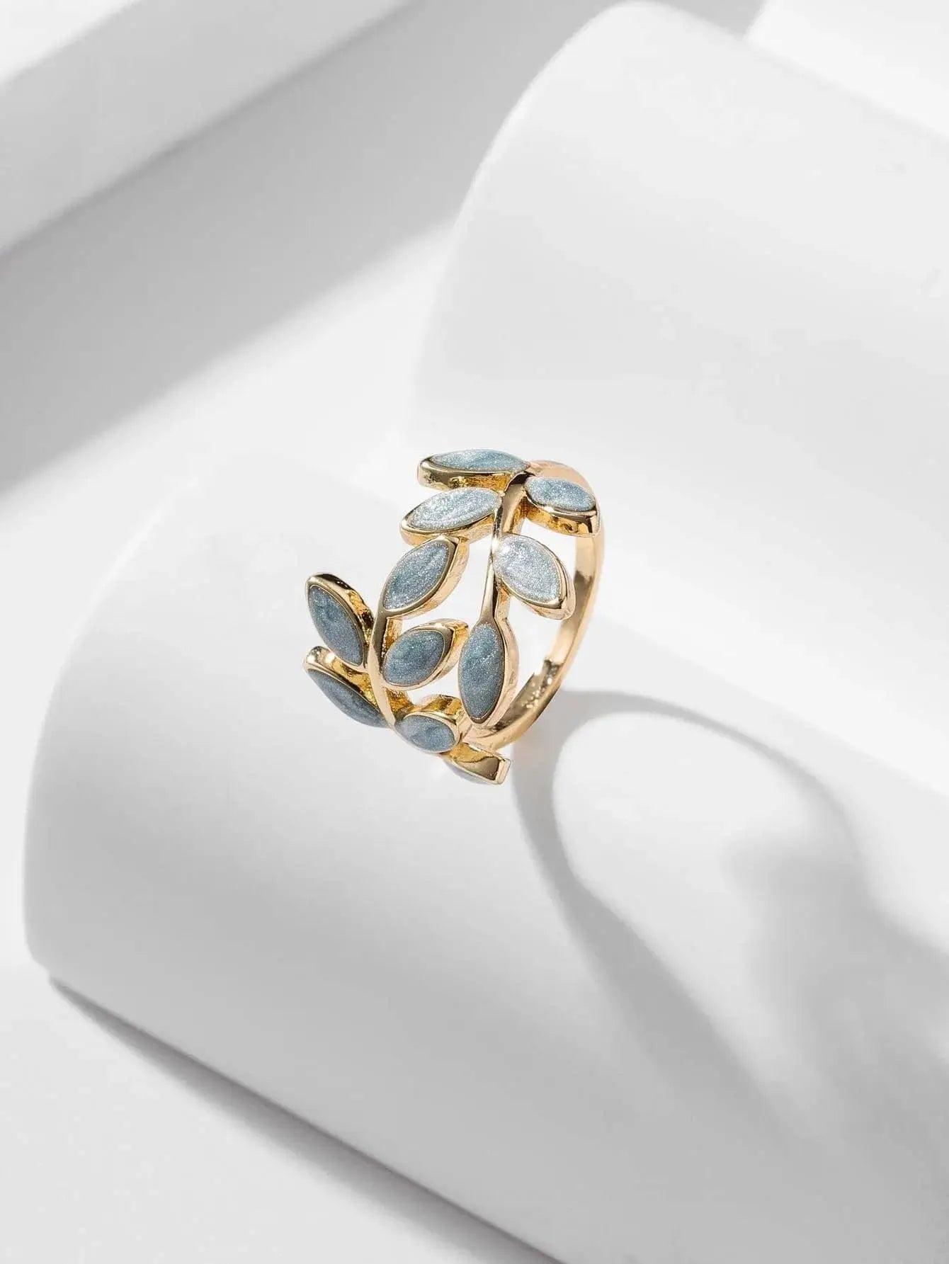 Bague ajustable en alliage de zinc avec incrustations en résine, disponible en rose pâle, blanc perlé, bleu ciel et rose lavande. Design doré avec motifs de feuilles en relief, parfaite pour rehausser votre style. Évitez le contact prolongé avec l'eau pour maintenir son éclat.