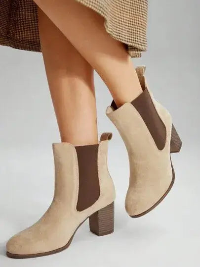 Bottines Chelsea à talon en suédine beige sable, agrémentées d'élastiques latéraux marron foncé. Design épuré à enfiler avec boucle arrière et talon bloc carré de hauteur moyenne. Construction extérieure et doublure en suédine, semelle extérieure en caoutchouc, semelle intérieure en similicuir. Style minimaliste et polyvalent. Entretien : nettoyage à sec recommandé.