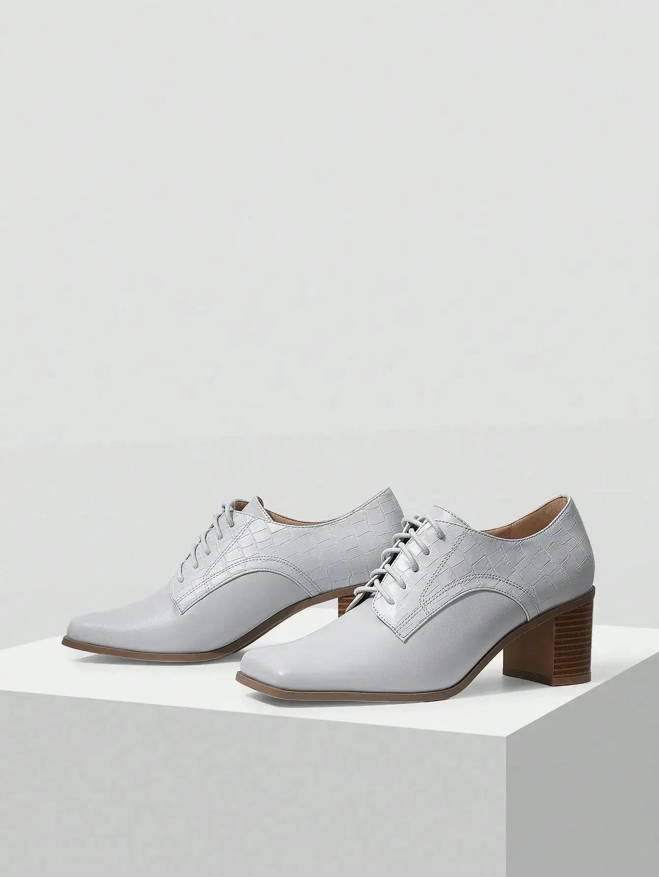 Chaussures Anglaise Talon Carré en similicuir haut de gamme. Design épuré avec bout carré et talon épais de hauteur moyenne pour un confort optimal. Disponible en gris classique, ces chaussures présentent un motif uni et des lacets raffinés. Pour l'entretien, nettoyer avec un chiffon doux et sec.