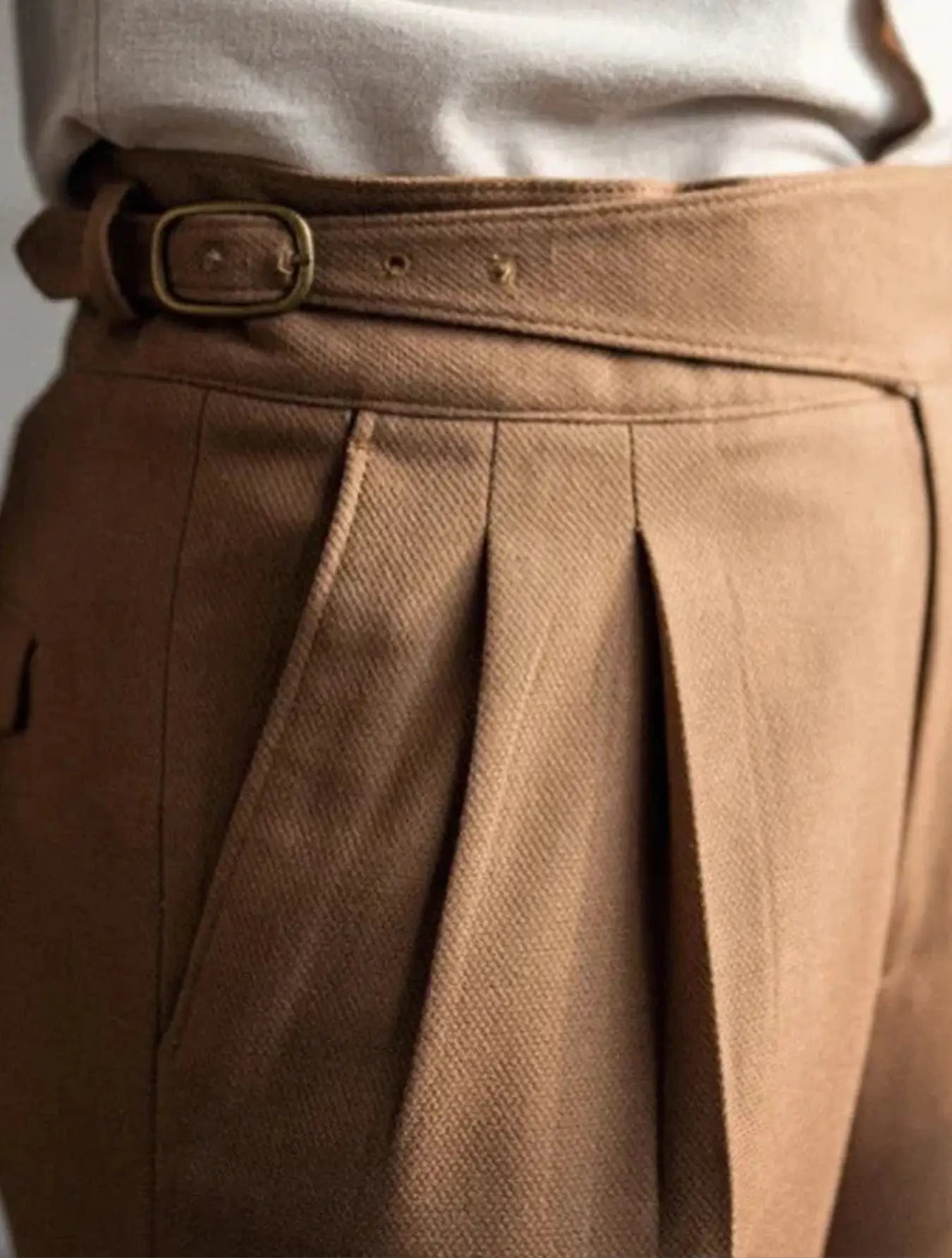 Pantalon taille haute en 100% polyester, résistant aux plis et durable. Coupe droite avec ceinture intégrée, boucle de réglage, plis frontaux et ourlet plié à la cheville. Disponible en blanc cassé, marron et marron clair. Tissu légèrement texturé, doux, avec poches latérales. Lavage en machine à froid recommandé.