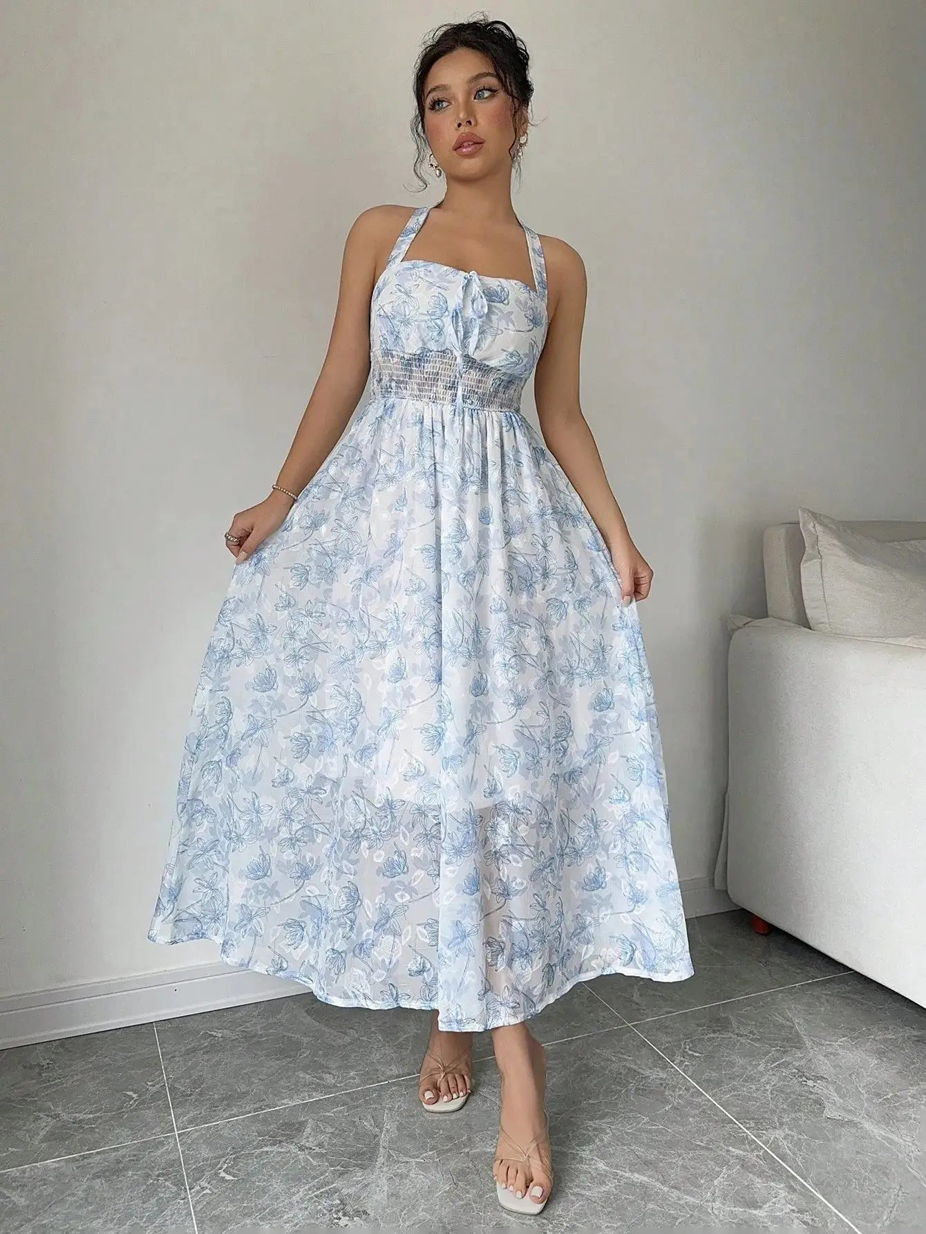 Robe longue bohème en polyester léger, imprimée floral bleu ciel. Encolure ras-du-cou, dos-nu, et buste froncé pour une silhouette élégante. Taille haute élastiquée et coupe évasée pour confort. Longueur jusqu'aux chevilles, doublée pour opacité. Lavage en machine ou nettoyage à sec recommandé.