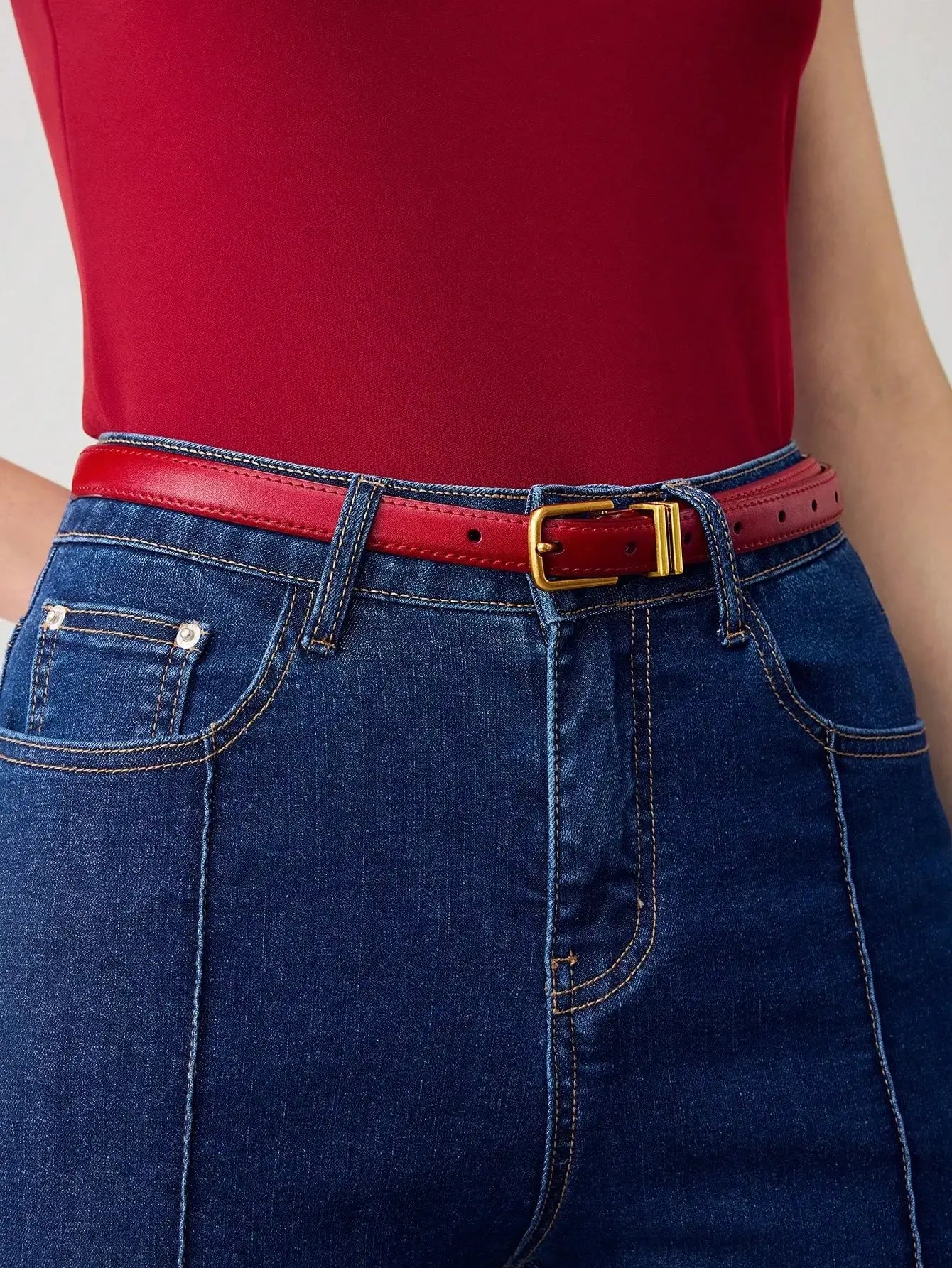 Ceinture femme en similicuir rouge, avec boucle dorée. Design lisse et finition brillante. Conçue pour ajouter une touche chic et contemporaine à vos tenues. Évitez l'exposition prolongée à l'humidité pour en préserver l'éclat.