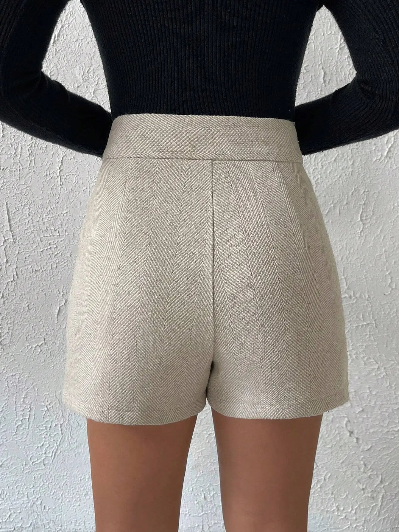 Short à chevrons beige, élégant et sophistiqué. Taille haute ajustée, détails plissés à l'avant, poches latérales et deux boutons dorés à la taille. Confectionné en mélange de fibres naturelles et synthétiques pour une texture structurée. Lavage à la main ou en machine à 30°C recommandé.