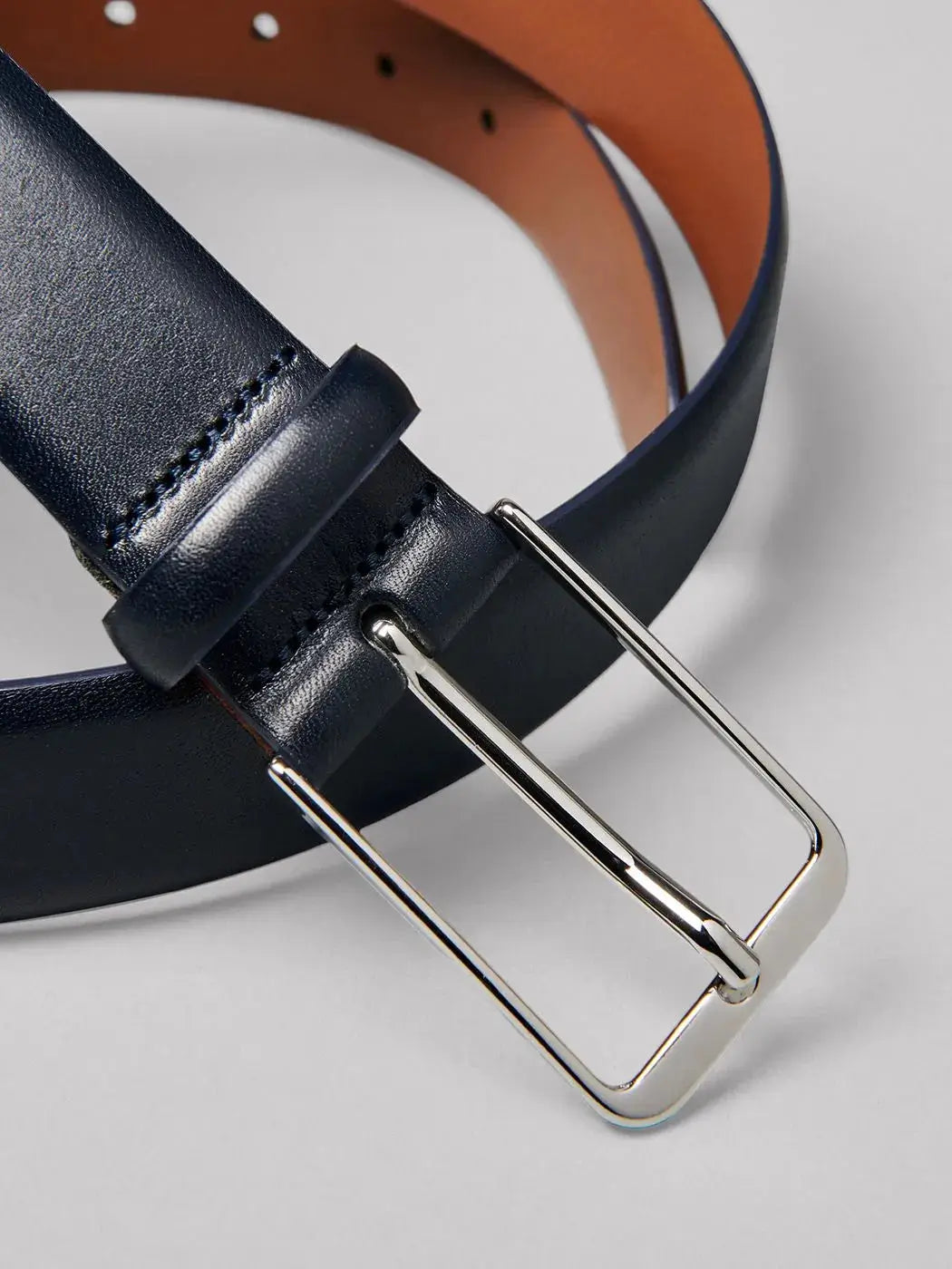 Ceinture en cuir noir avec boucle rectangulaire argentée, intérieur marron, idéale pour un look formel et élégant.