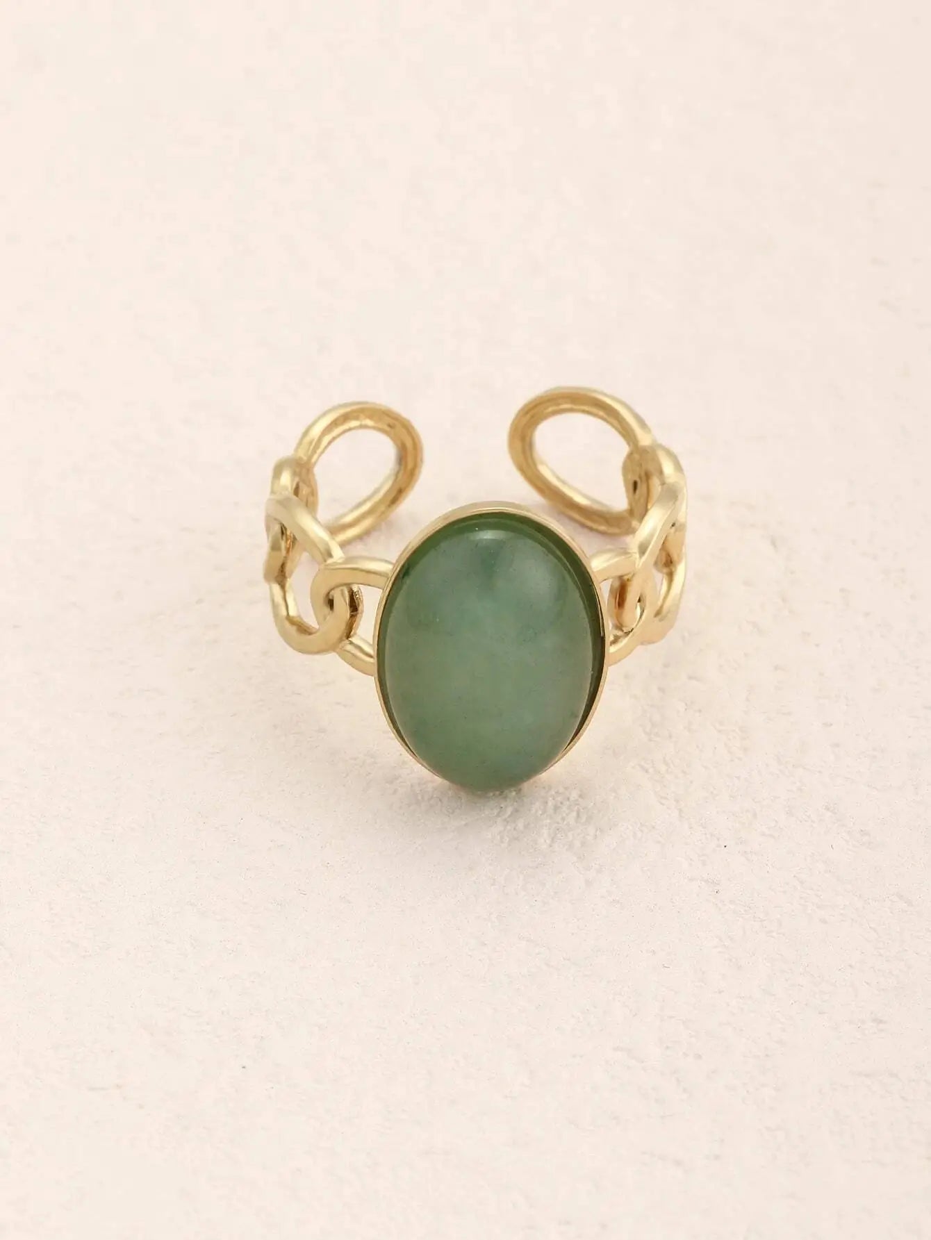 Bague ajustable en alliage de zinc plaqué or, avec une pierre ovale verte en résine. Bandeau en maillons torsadés, diamètre de 1,8 cm et poids de 3,8 g. Nettoyage à la main recommandé pour préserver l’éclat.