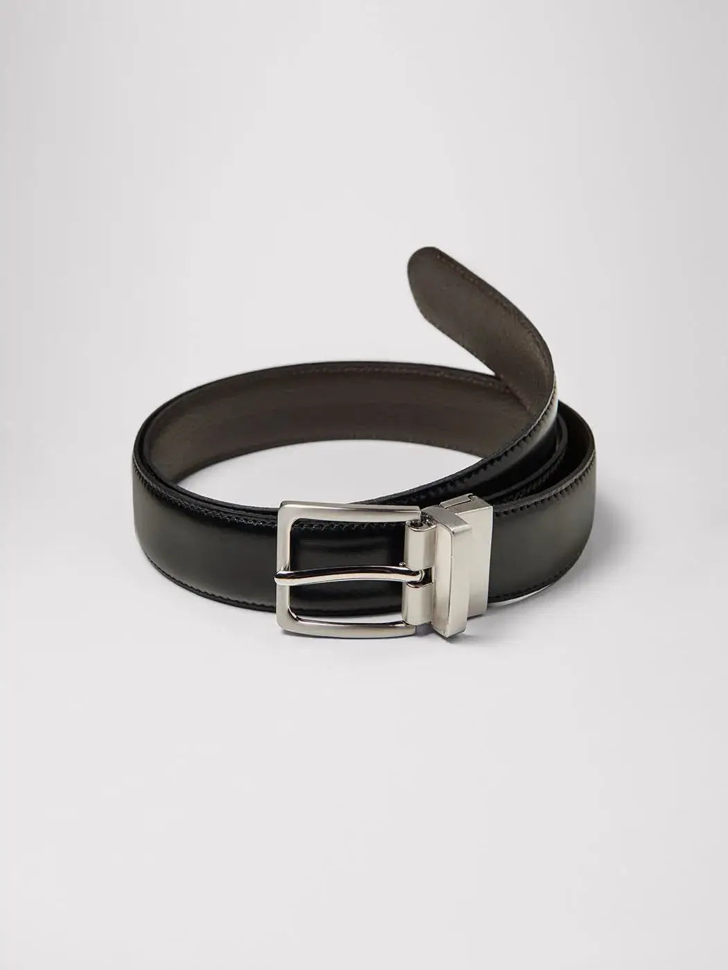 Ceinture réversible en cuir, disponible en noir et chocolat. Composée de croûte de cuir avec une boucle rectangulaire en zamak brossé et des surpiqûres ton sur ton. Largeur de 3,3 cm avec cinq trous d'ajustement. Entretien : éviter lavage, blanchiment, repassage et séchage en machine.