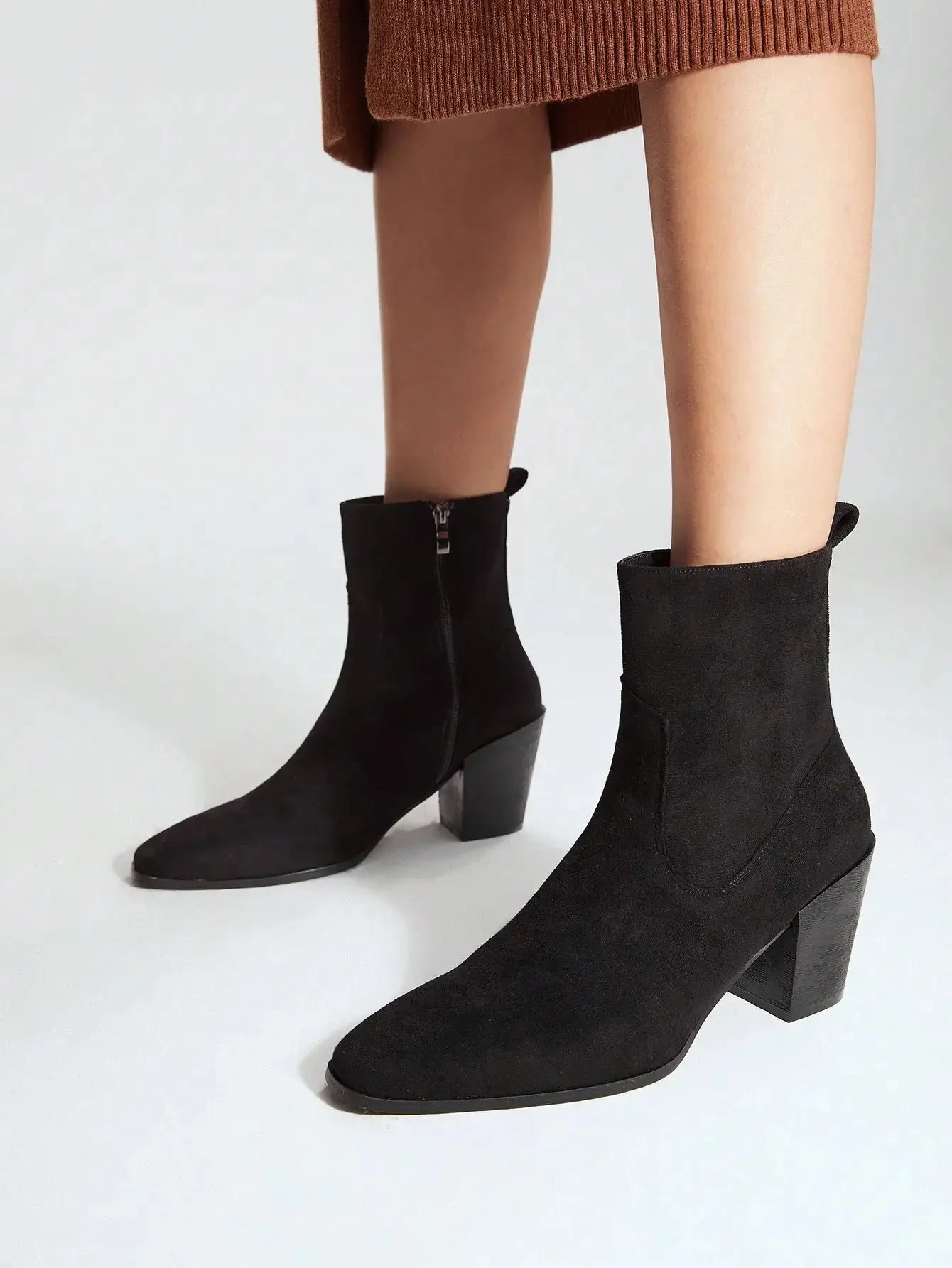 Bottines noires en imitation daim de qualité supérieure. Design élégant avec bout légèrement pointu et fermeture éclair latérale. Talons carrés pour un confort optimal et texture veloutée pour un effet luxueux. Nettoyage à sec recommandé pour maintenir l'éclat du matériau.